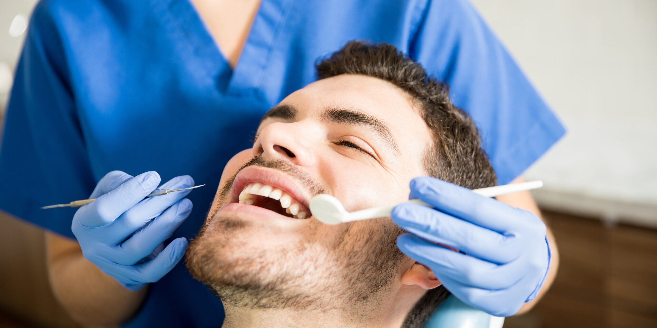 Man Receiving Treatment From Dentist In Dental Clinic